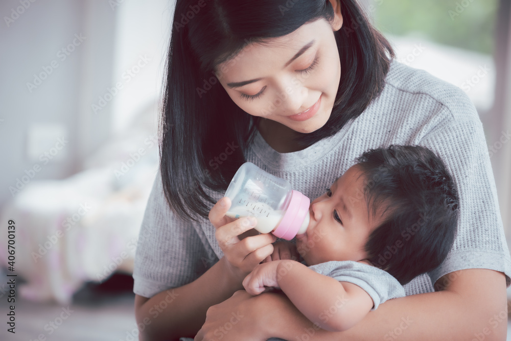 Young asian mother feeding baby from milk bottle. Young asian mother feeding baby from milk bottle.