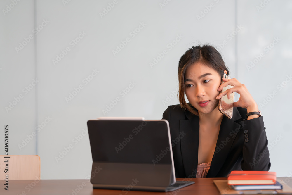 Portrait of businesswoman talking on the phone while working at a worktable in an office room. Portrait of businesswoman talking on the phone while working at a worktable in an office room.