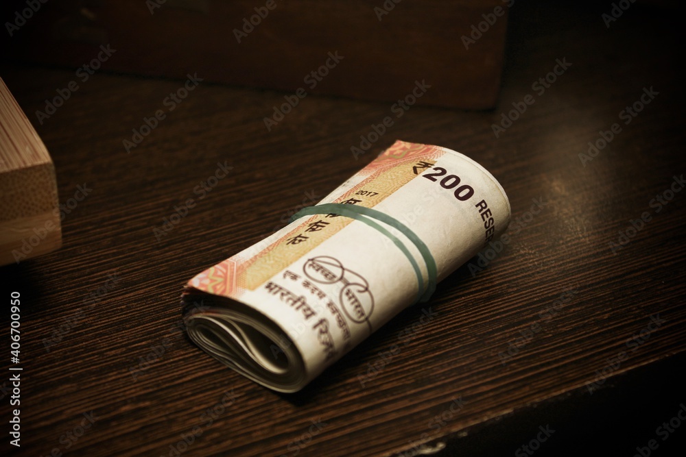 Fototapeta premium roll of two hundred rupees cash. Indian currency notes on table