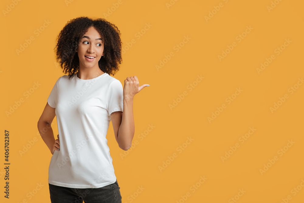 Smiling young pretty african american curly lady in white t-shirt sees amazing thing, gestures, show free space Smiling young pretty african american curly lady in white t-shirt sees amazing thing, gestures, show free space