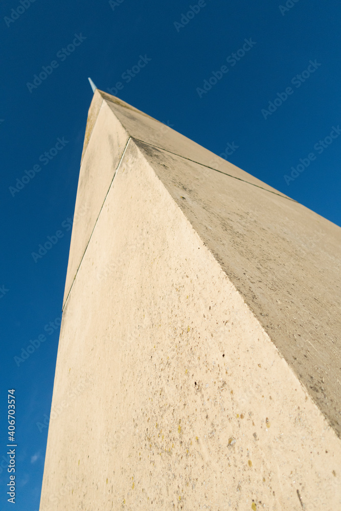 A large stone and cement oblisque tower photographed from below against a vivid blue sky. Monuments and towers high in the sky. A large stone and cement oblisque tower photographed from below against a vivid blue sky. Monuments and towers high in the sky.