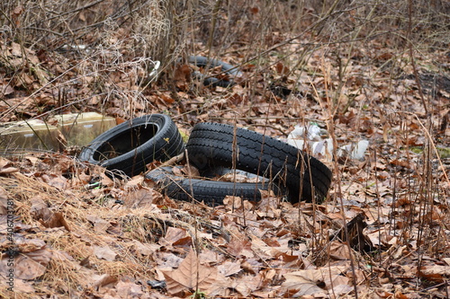 Discarded used tires eyesore left on ground in woods creating environmental pollution photo