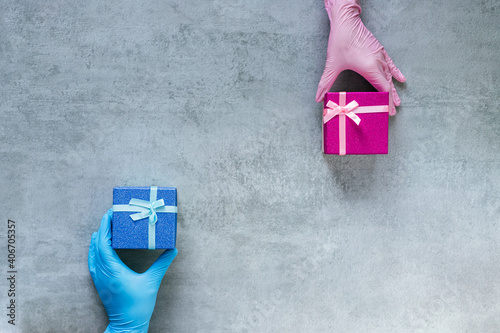 Gifts of love. Protection from Covid-19. Male and female hands in medical gloves hold pink and blue gift boxes on the copy space. Congratulations on the anniversary. Valentine's Day.