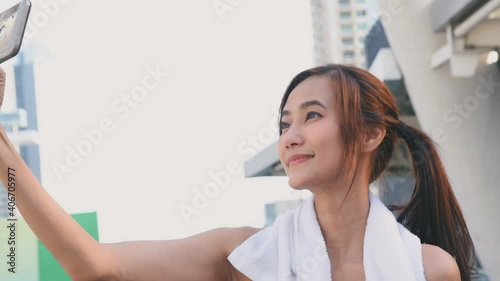 Asian woman in sport outfit take a break and selfie herself to online social media after running workout in the city with metropolis background