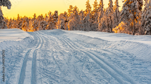 Cross country skiing slope running through a snow covered frozen forest at dusk.