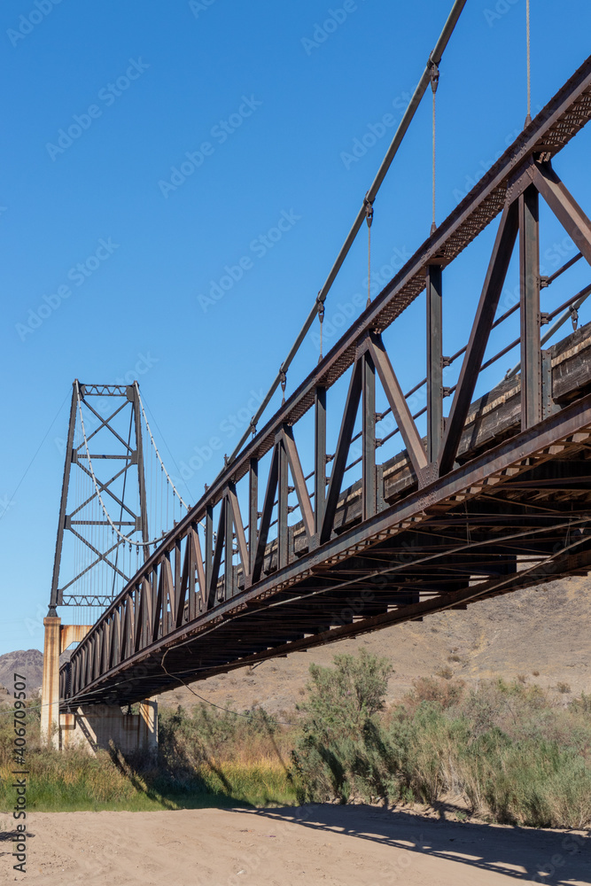 Long rusty expanse of old bridge across dry river bed