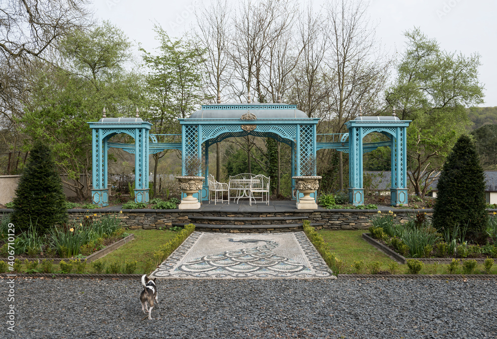 Fototapeta premium A beautiful antique decorative victorian style metal summer house awning in a green flower garden in an english countryside. Traditional victorian england architecture.