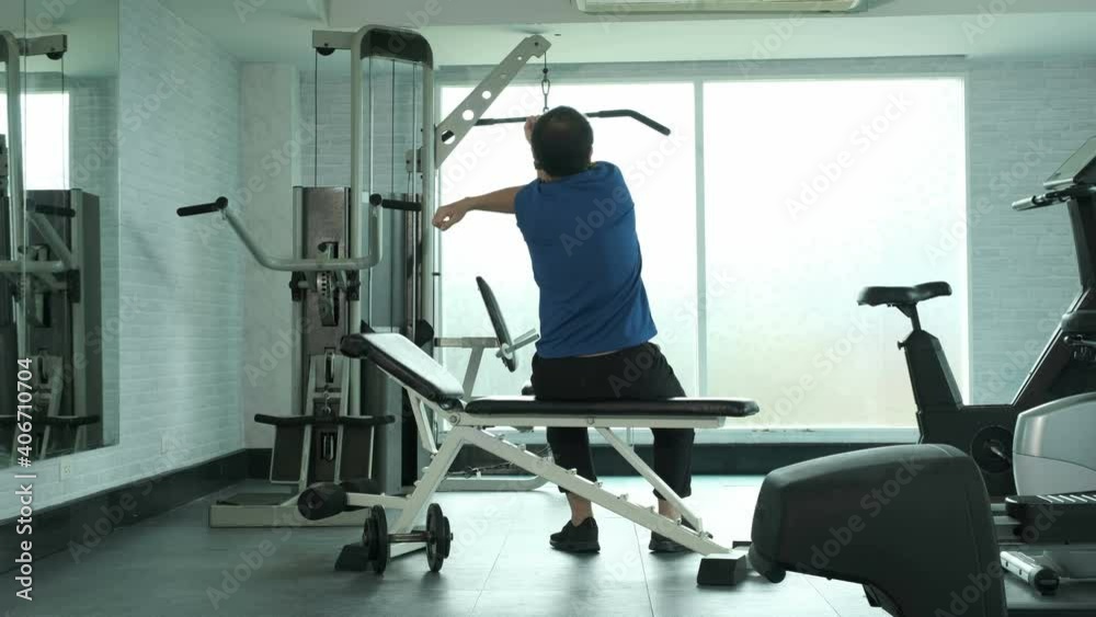 Young Asian man in sportwear sitting on bench and shoulder stretching pulling elbow and twisting body. sport, bodybuilding, fitness and people concept Young Asian man in sportwear sitting on bench and shoulder stretching pulling elbow and twisting body. sport, bodybuilding, fitness and people concept