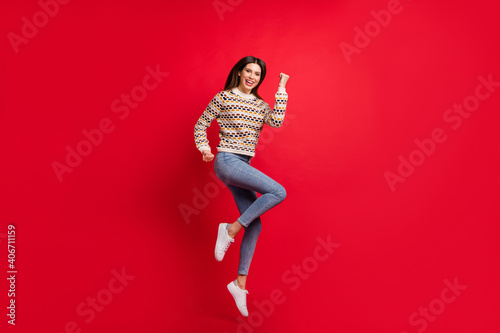 Full length body size photo of jumping up girl gesturing like winner laughing isolated bright red color background