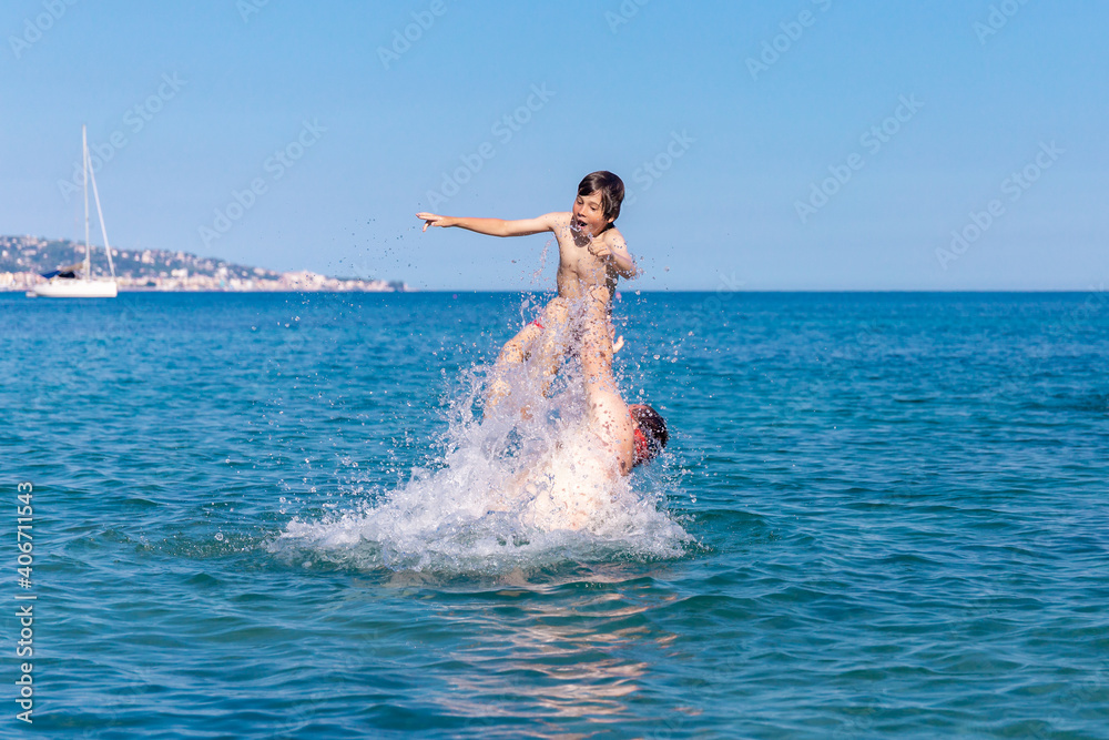A man with his son swimming and playing in the sea.  A father throws a boy over the water. Family having fun in water