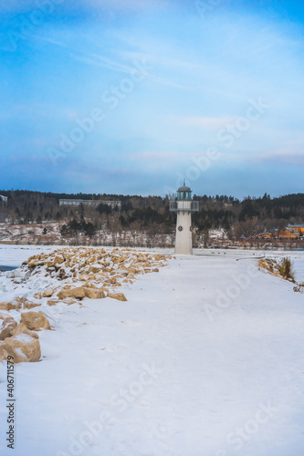 Lighthouse on a winter day on a frozen snow-covered river. Beautiful winter landscape
