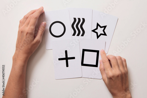 Manos de mujer haciendo truco de mentalismo con  cartas Zener. Vista desde arriba. Fondo blanco. photo