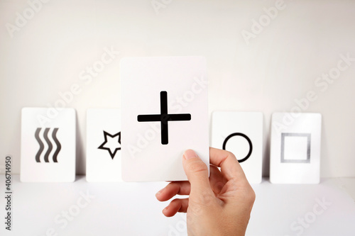 Mano de mujer mostrando una carta Zener con una cruz. Fondo blanco