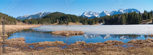 tranquil lake Geroldsee with ice cover and reflecting montain range at early springtime, Karwendel alps bavaria