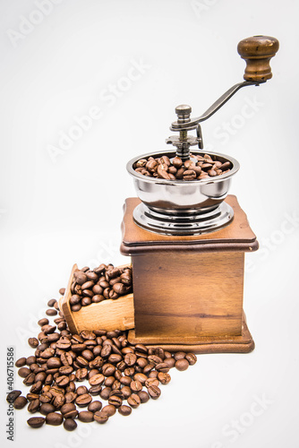 
A traditional hand-cranked coffee grinder, coffee beans overflow from the drawer and cone grinders.