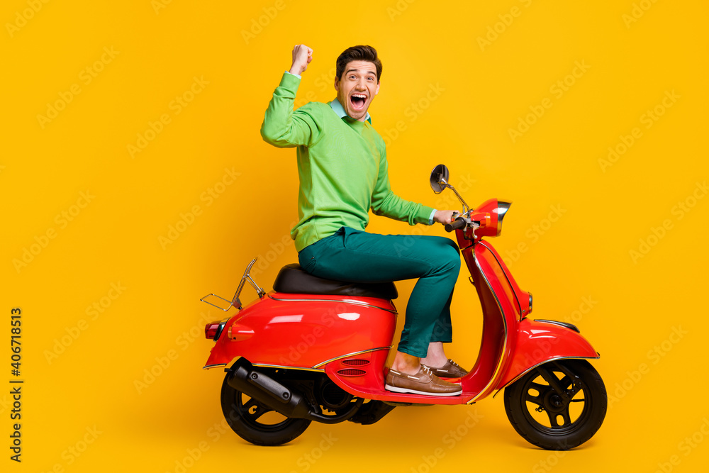 Fototapeta premium Full body profile photo of delighted guy fist up open mouth shout yeah sit in bike isolate don yellow color background