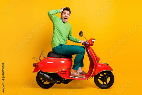 Full size profile portrait of impressed person on moped hand on head open mouth isolated on yellow color background