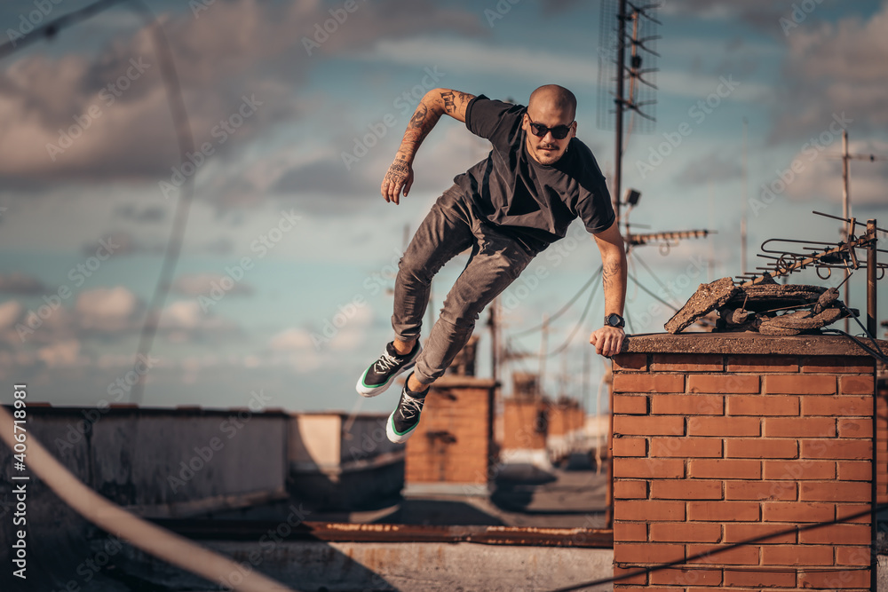 Urban young man jumping and doing parkour on top of the building Urban young man jumping and doing parkour on top of the building