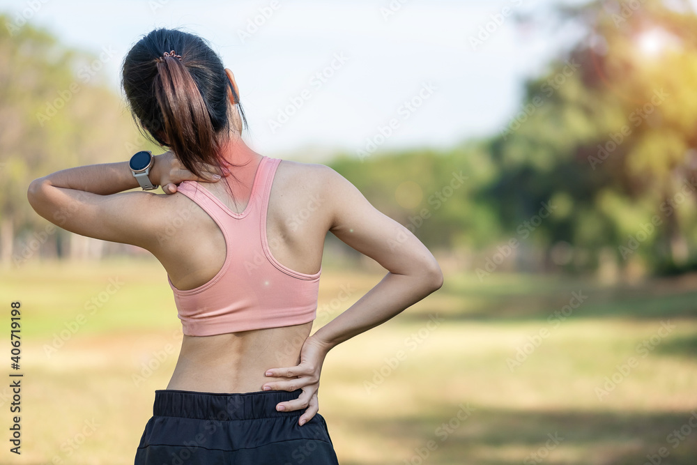 Young fitness woman holding her sports injury neck, muscle painful during training. Asian runner female having body problem after exercise outside in summer Young fitness woman holding her sports injury neck, muscle painful during training. Asian runner female having body problem after exercise outside in summer