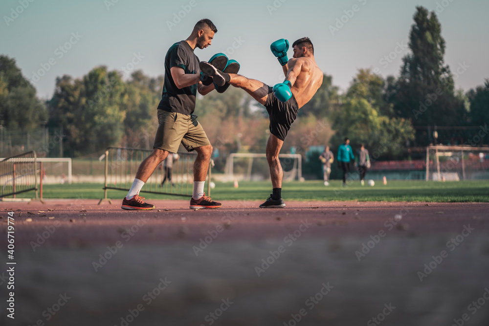 Fototapeta premium Two athletic young men boxing . Men training outdoors . Training kickboxing. Two males boxing outdoors. Sparring training box outside sport concept. 