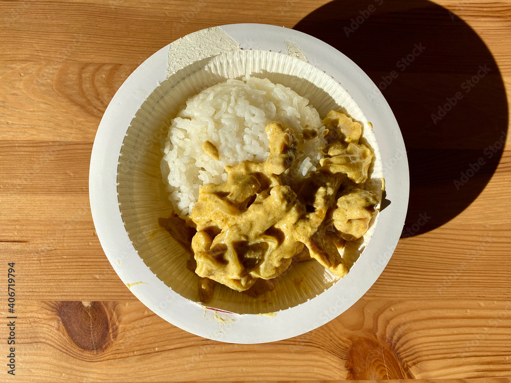 Take Away Rice with Curry Sauce Chicken in Plastic Bowl Plate Package Container on Wooden Table. Take Away Rice with Curry Sauce Chicken in Plastic Bowl Plate Package Container on Wooden Table.
