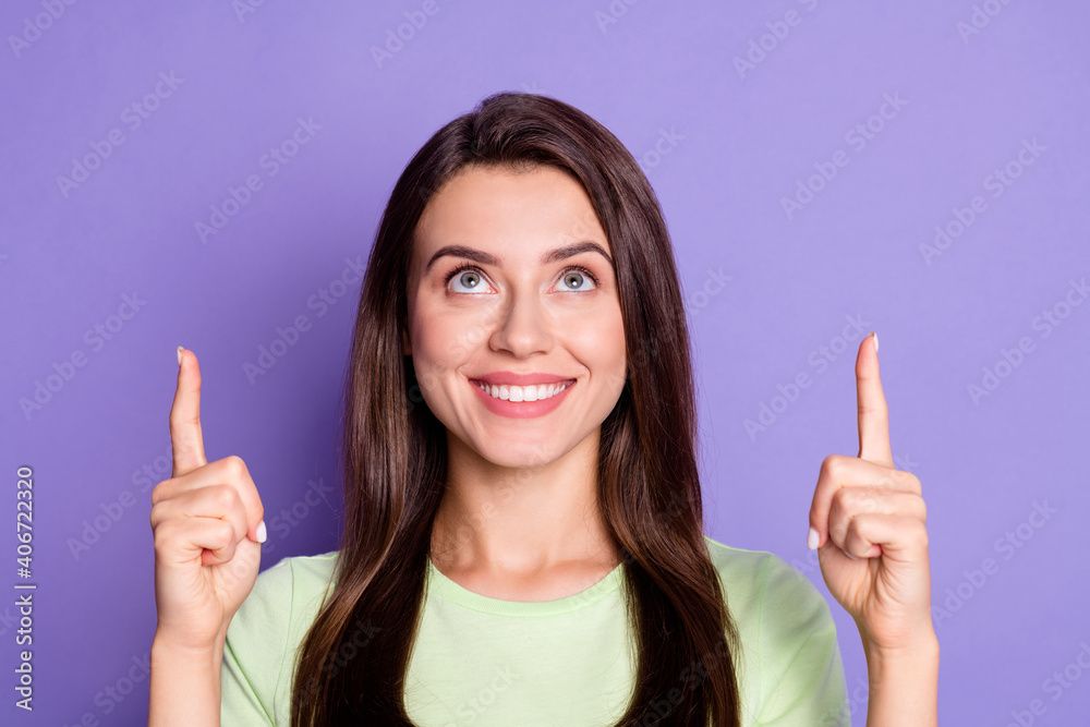 Photo portrait of pretty smiling girl pointing up at copyspace with fingers looking isolated on vivid violet color background Photo portrait of pretty smiling girl pointing up at copyspace with fingers looking isolated on vivid violet color background