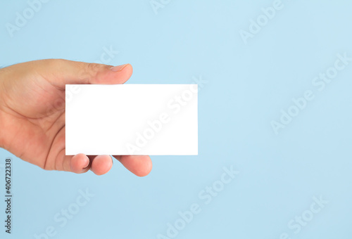 Businessman hand holding blank business card on blue background