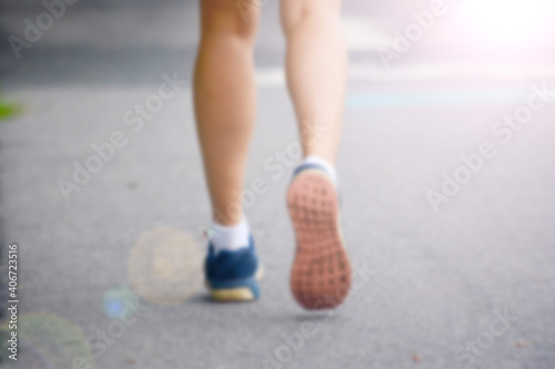  an athletic pair of legs running or jogging on a path during sunrise or sunset - healthy lifestyle concept done with a soft glowing filter blurred out so text can be placed over the image