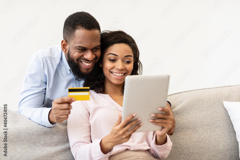 Black couple using tablet and debit credit card at home Black couple using tablet and debit credit card at home
