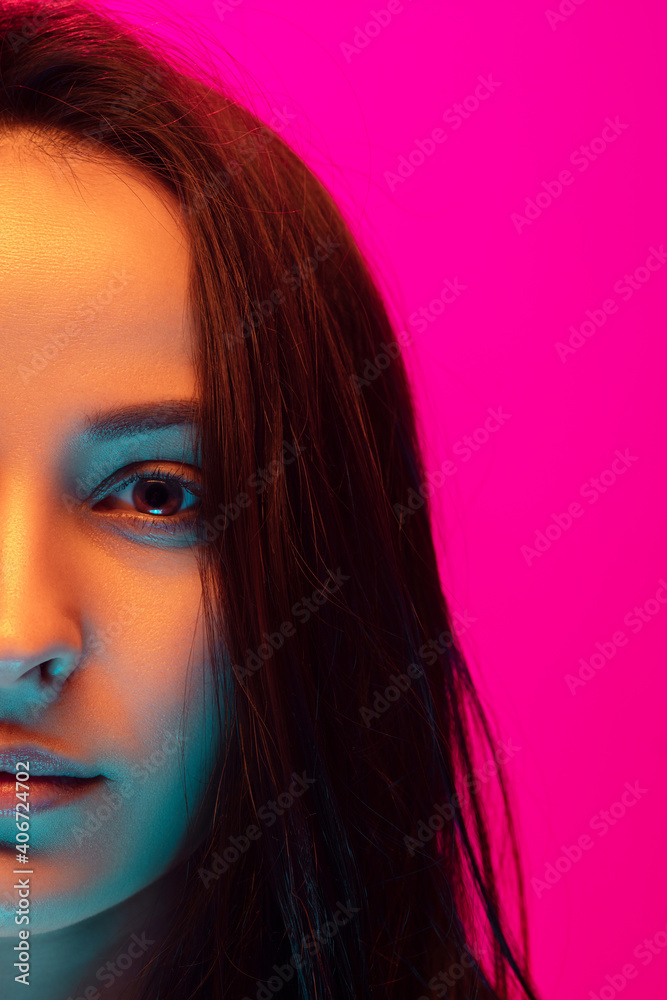 Close up half-full caucasian woman's portrait isolated on pink studio background in mixed neon light. Beautiful female model. Concept of human emotions, facial expression, sales, ad, fashion. Beauty. Close up half-full caucasian woman's portrait isolated on pink studio background in mixed neon light. Beautiful female model. Concept of human emotions, facial expression, sales, ad, fashion. Beauty.