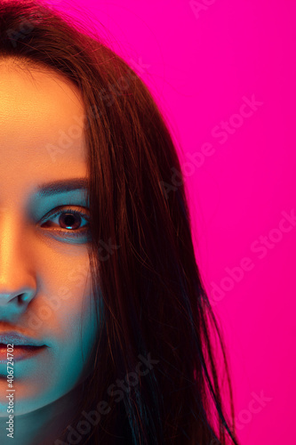 Close up half-full caucasian woman's portrait isolated on pink studio background in mixed neon light. Beautiful female model. Concept of human emotions, facial expression, sales, ad, fashion. Beauty.