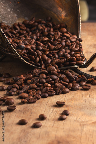 Coffee beans in a bronze bowl on a wooden background