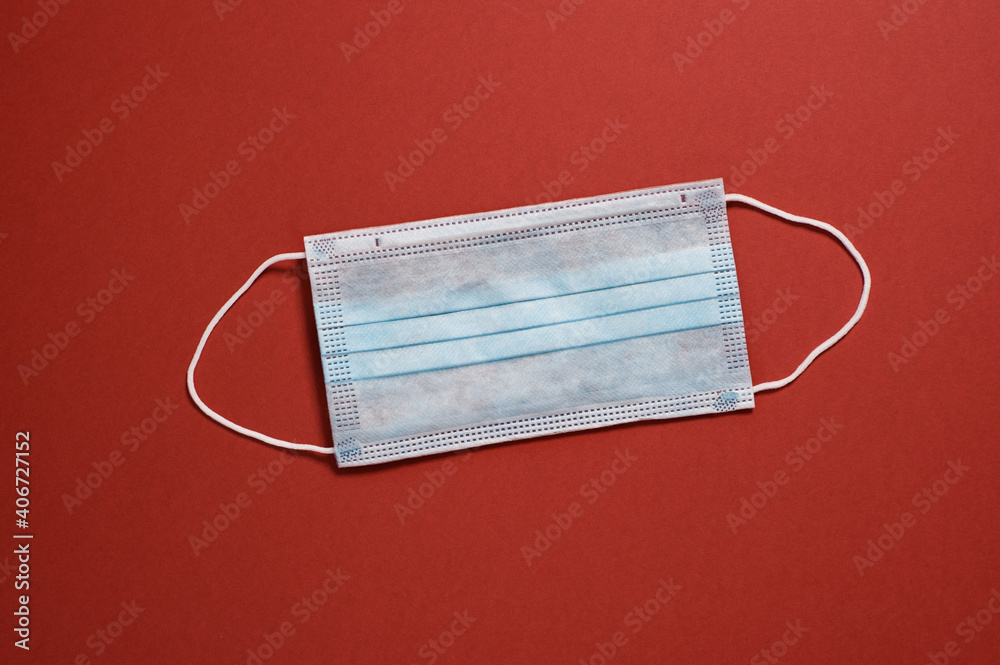disposable medical mask on a red background top view