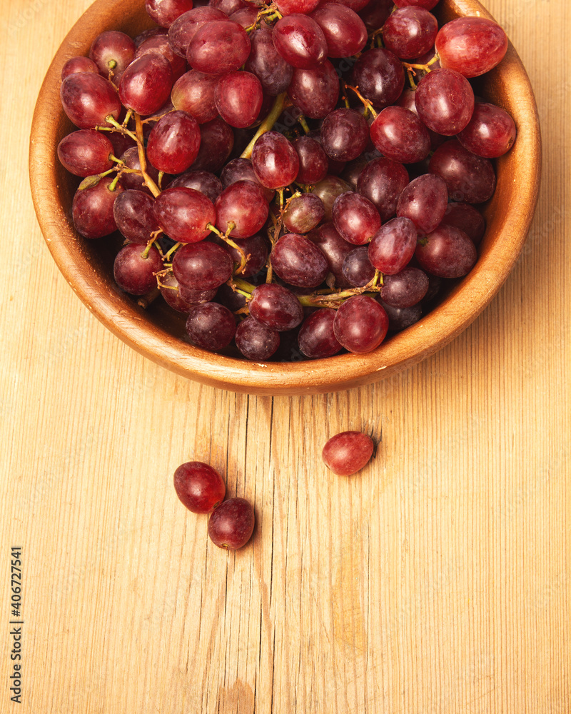 Fresh ripe grape berries in bowl on brown wooden background. Fresh ripe grape berries in bowl on brown wooden background.