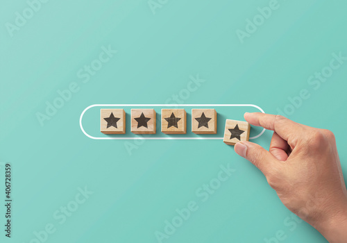 Improve rating, increase ranking, improve customer satisfaction  concept. Hand putting wooden blocks with star icon in progress bar on turquoise background. photo