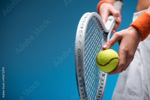 Fototapeta partial view of sportive young woman holding tennis racket and ball while playin