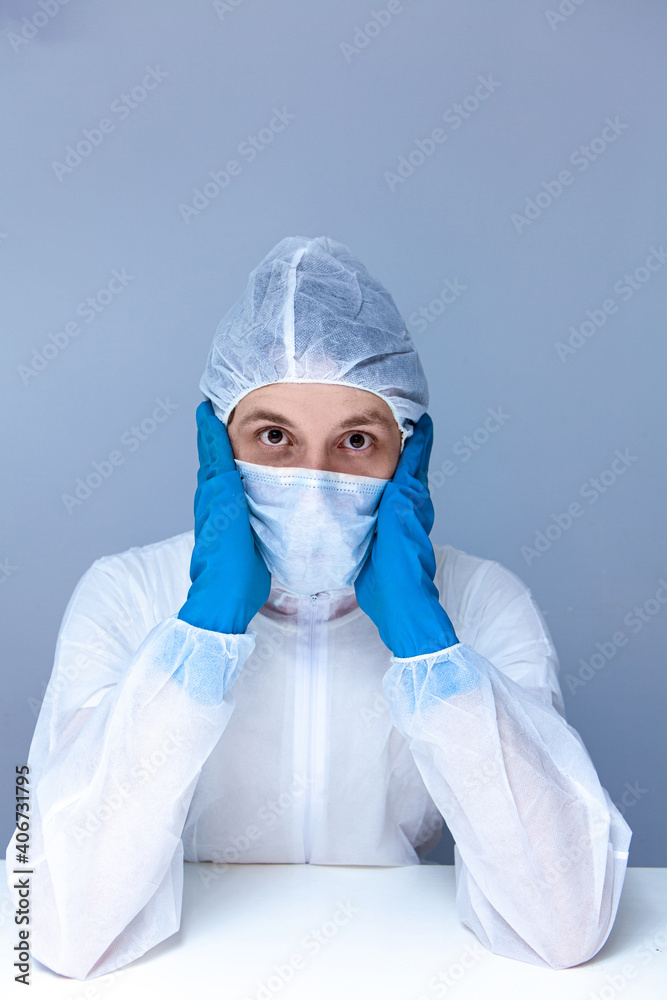 man in protective suit, gloves and mask on his face holding his head pretending to panic or fear. The concept of health.