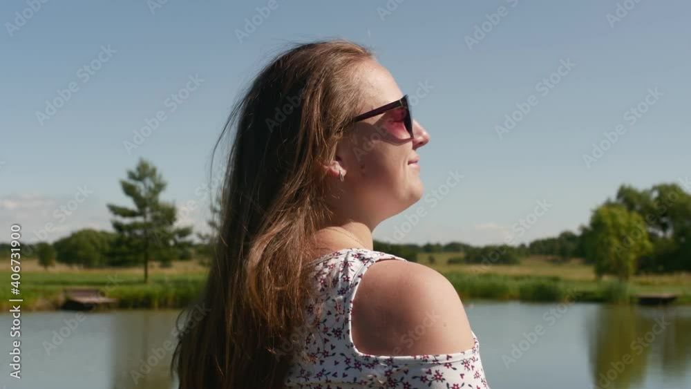 Back view of young woman standing and relaxing on the pond in summer. Back view of young woman standing and relaxing on the pond in summer.