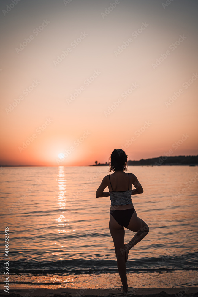 Young beautiful woman practicing pose from yoga on the beach at sunset. Female on beach exercising on vacation Young beautiful woman practicing pose from yoga on the beach at sunset. Female on beach exercising on vacation