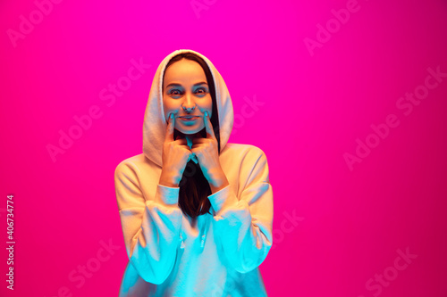 Smile. Caucasian woman's portrait isolated on pink studio background in mixed neon light. Beautiful female model. Concept of human emotions, facial expression, sales, ad, fashion. Copyspace.