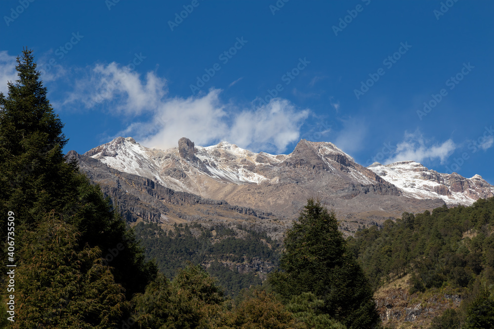 Landscape of the Iztaccihuatl Mountain covered in greenery under a blue sky in Mexico