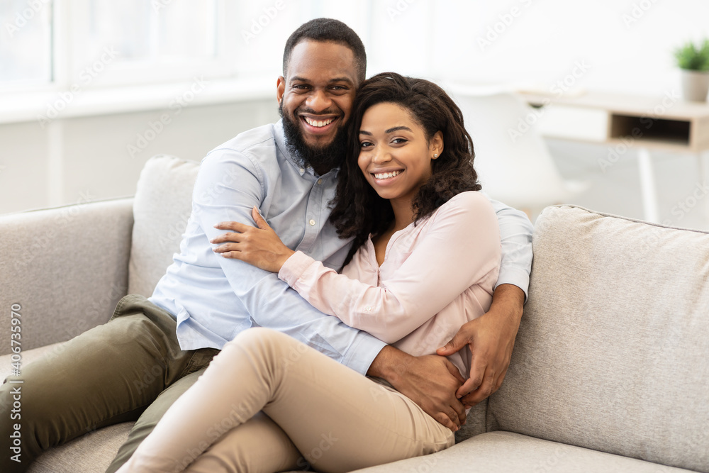 African american couple spending weekend together lying on sofa