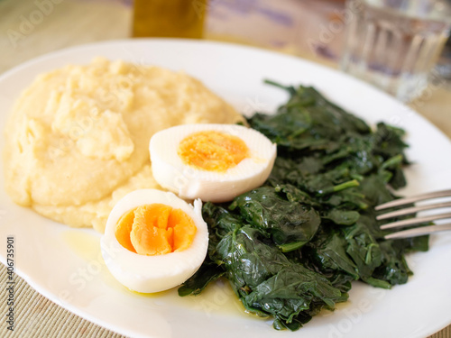 Plate of boiled spinach with mashed potatoes and a hard-boiled egg cut in half