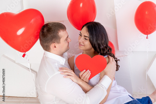 valentine's day, a guy with a beautiful girl look at each other with a loving look, which holds a big red heart