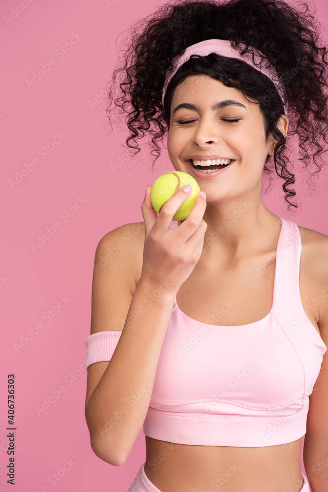 joyful young woman with closed eyes holding tennis ball isolated on pink joyful young woman with closed eyes holding tennis ball isolated on pink