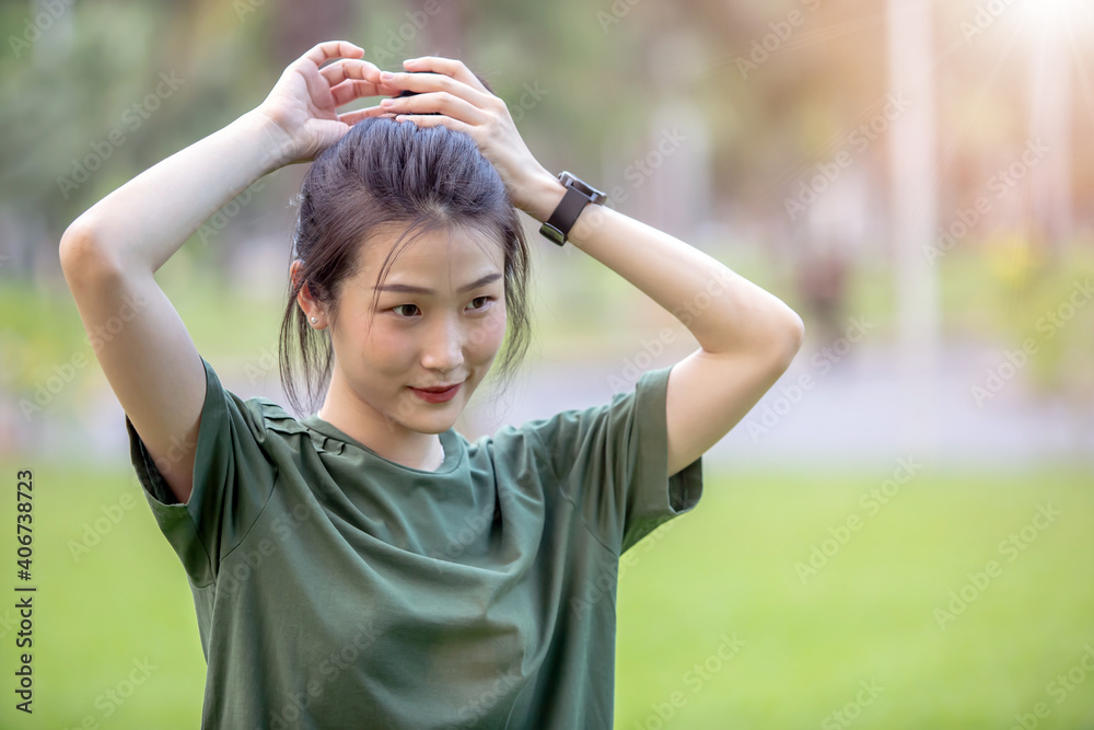 Young Asian woman tying her hair before exercise in the park