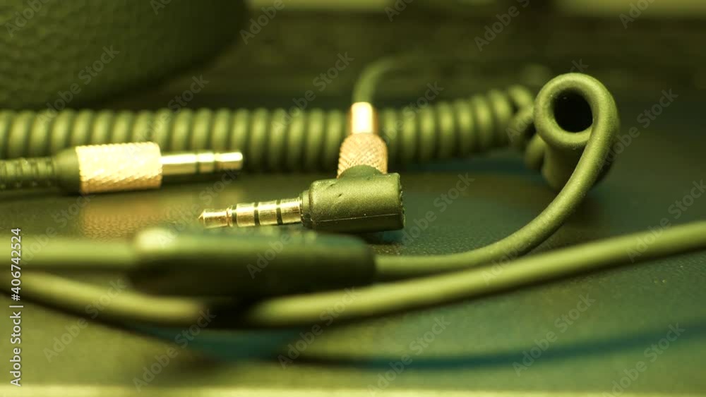 Music, stereo 3.5 mm cable on table in changing color led lamp lighting Music, stereo 3.5 mm cable on table in changing color led lamp lighting