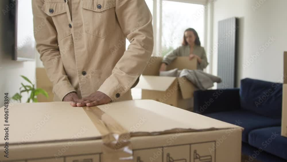 Close up of young couple in lounge at home packing removal boxes ready for house move - shot in slow motion