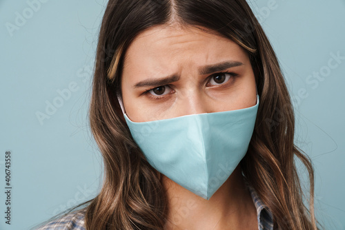 Unhappy girl in face mask posing and looking at camera