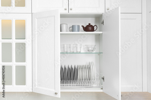 Open cabinet with different clean dishware in kitchen